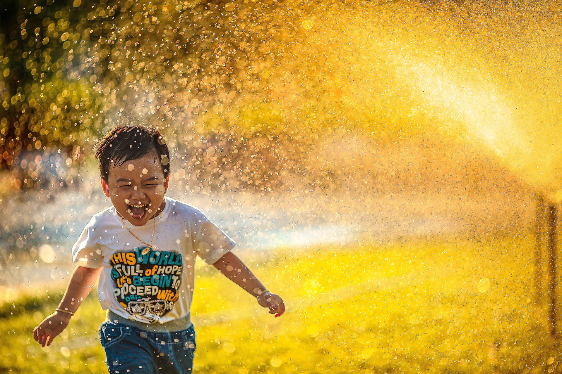 little boy running through sprinkler